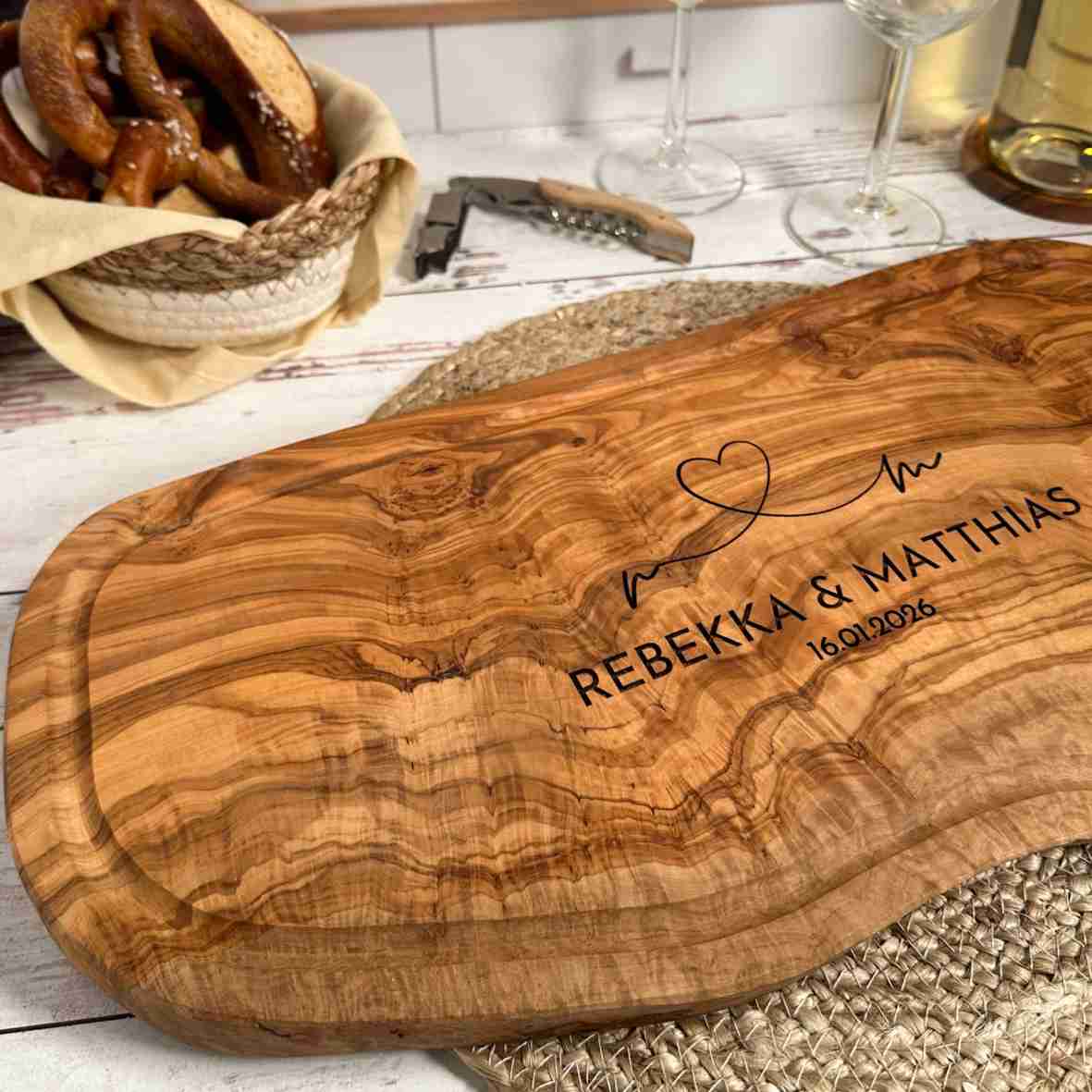 Personalisiertes Olivenholzbrett mit Herz-Gravur, Namen und Datum.