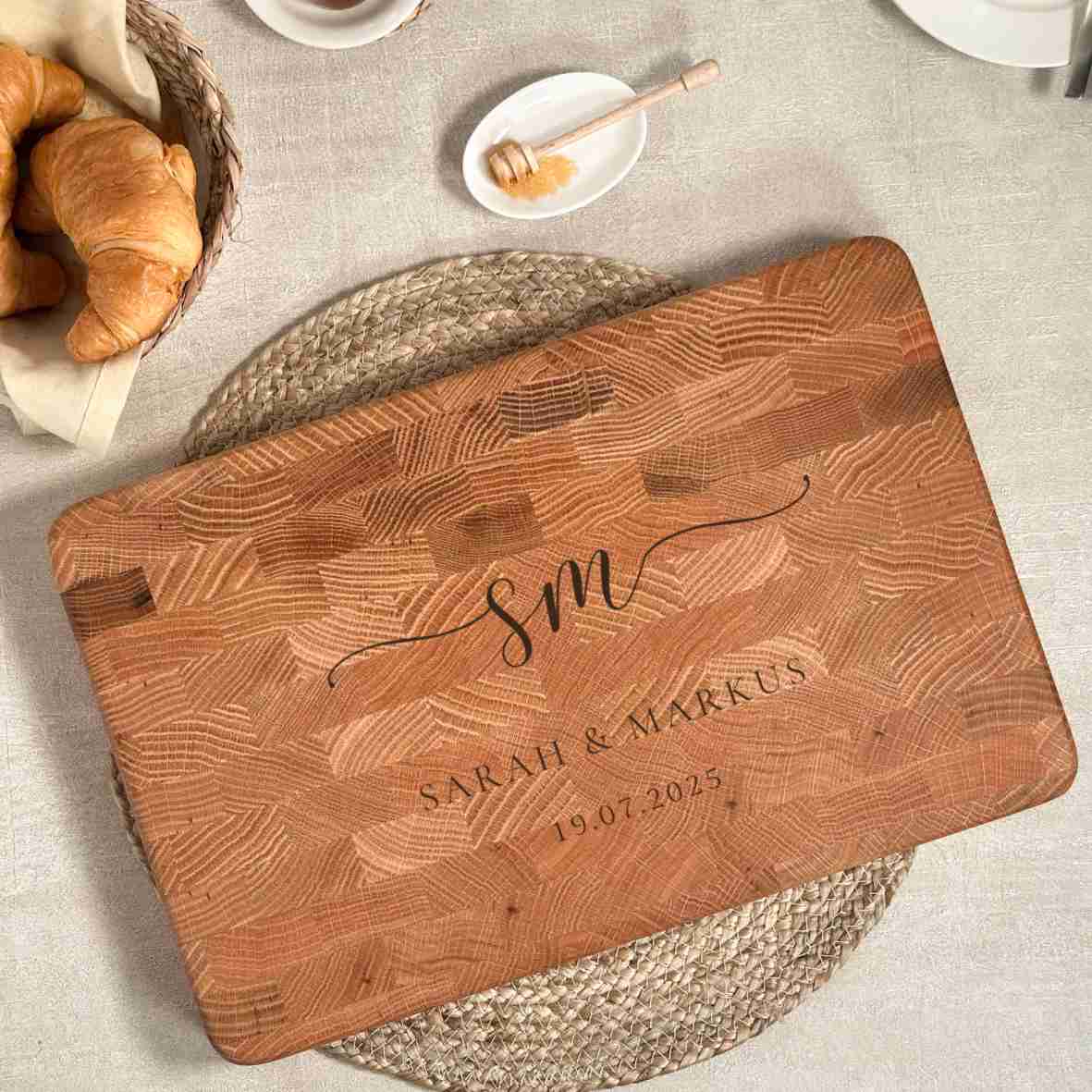 Personalisiertes Schneidebrett aus Eiche-Stirnholz mit gravierten Initialen „SM“, Namen „Sarah & Markus“ und Datum, als elegantes Hochzeitsgeschenk auf hellem gedecktem Tisch.
