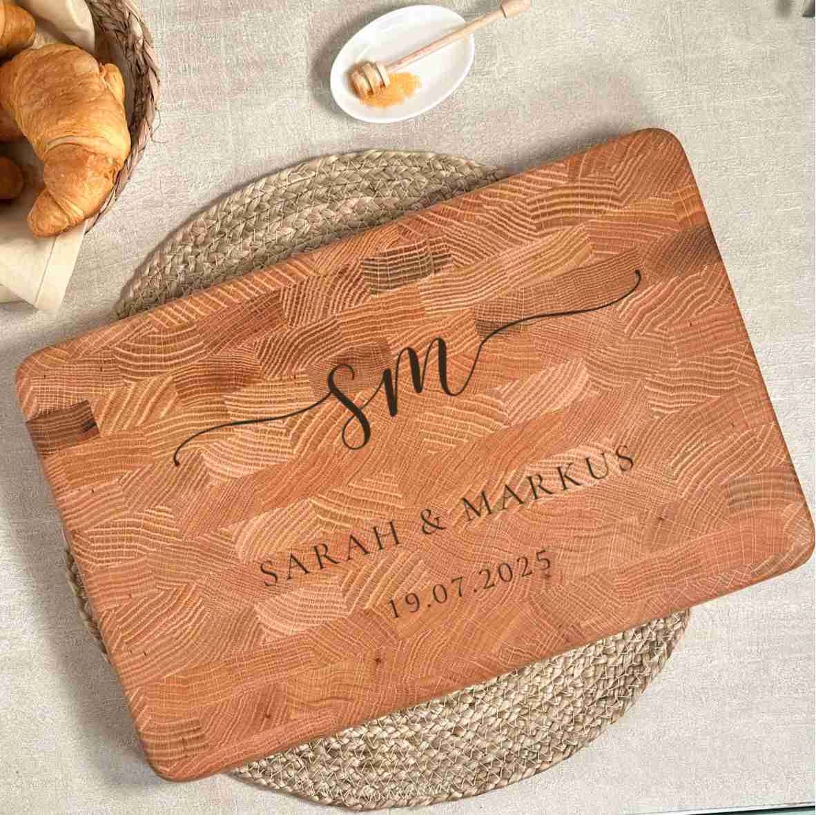 Personalisiertes Schneidebrett aus Eiche-Stirnholz mit gravierten Initialen „SM“, Namen „Sarah & Markus“ und Datum, als elegantes Hochzeitsgeschenk auf hellem gedecktem Tisch.