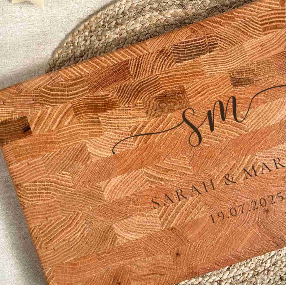 Personalisiertes Schneidebrett aus Eiche-Stirnholz mit gravierten Initialen „SM“, Namen „Sarah & Markus“ und Datum, als elegantes Hochzeitsgeschenk auf hellem gedecktem Tisch.