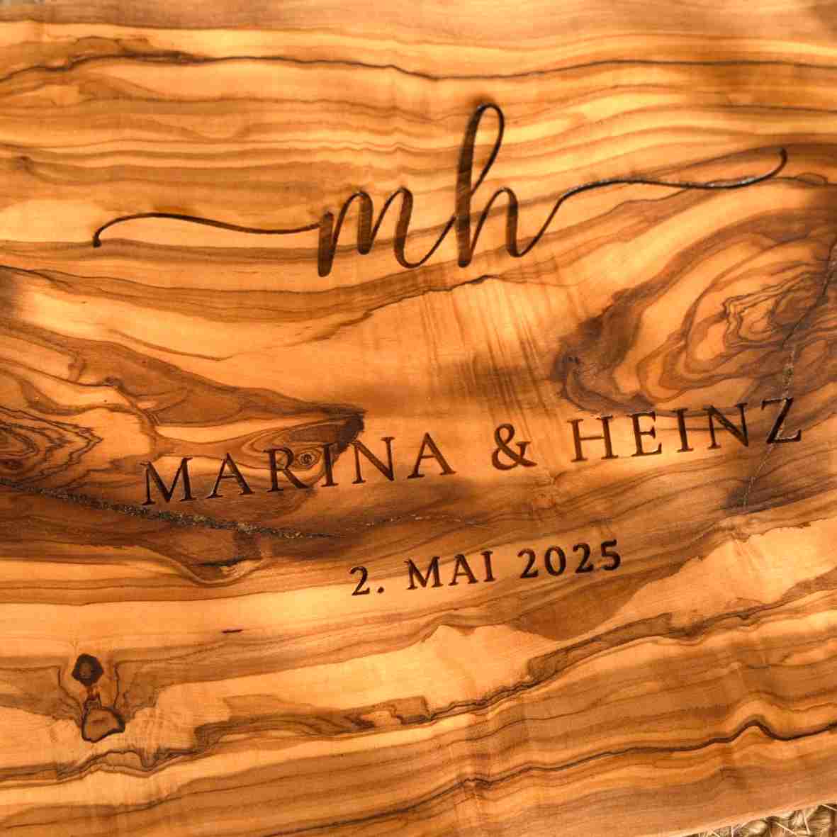 Graviertes Olivenholzbrett mit Initialen, Namen „Marina & Heinz“ und Datum „2. Mai 2025“ – personalisiertes Geschenk zur Hochzeit oder Einweihung.