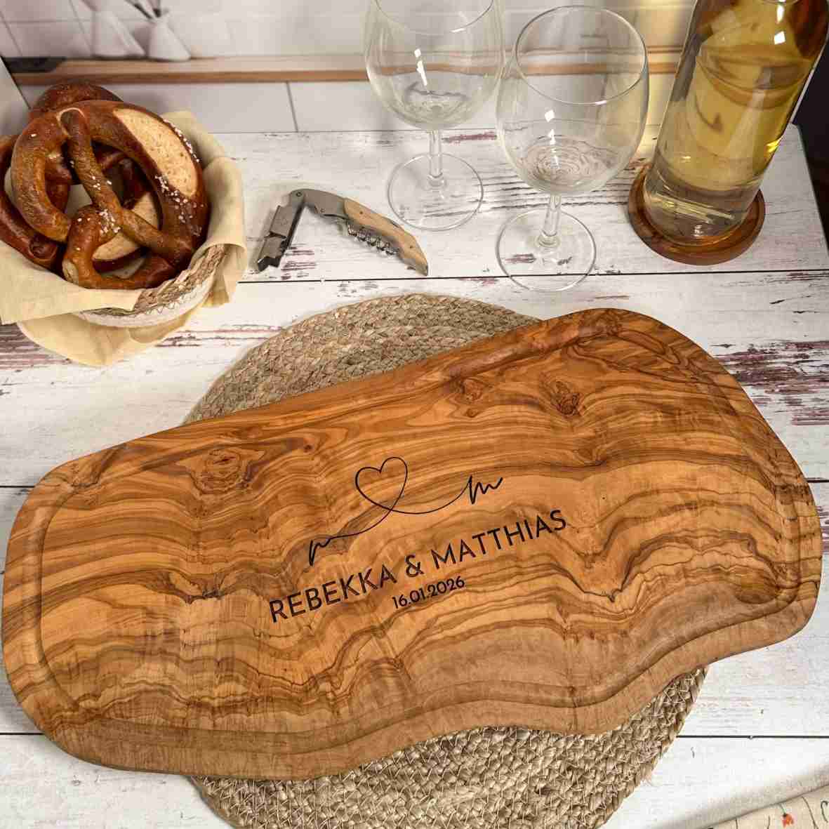 Personalisiertes Olivenholzbrett mit Herz-Gravur, Namen und Datum.