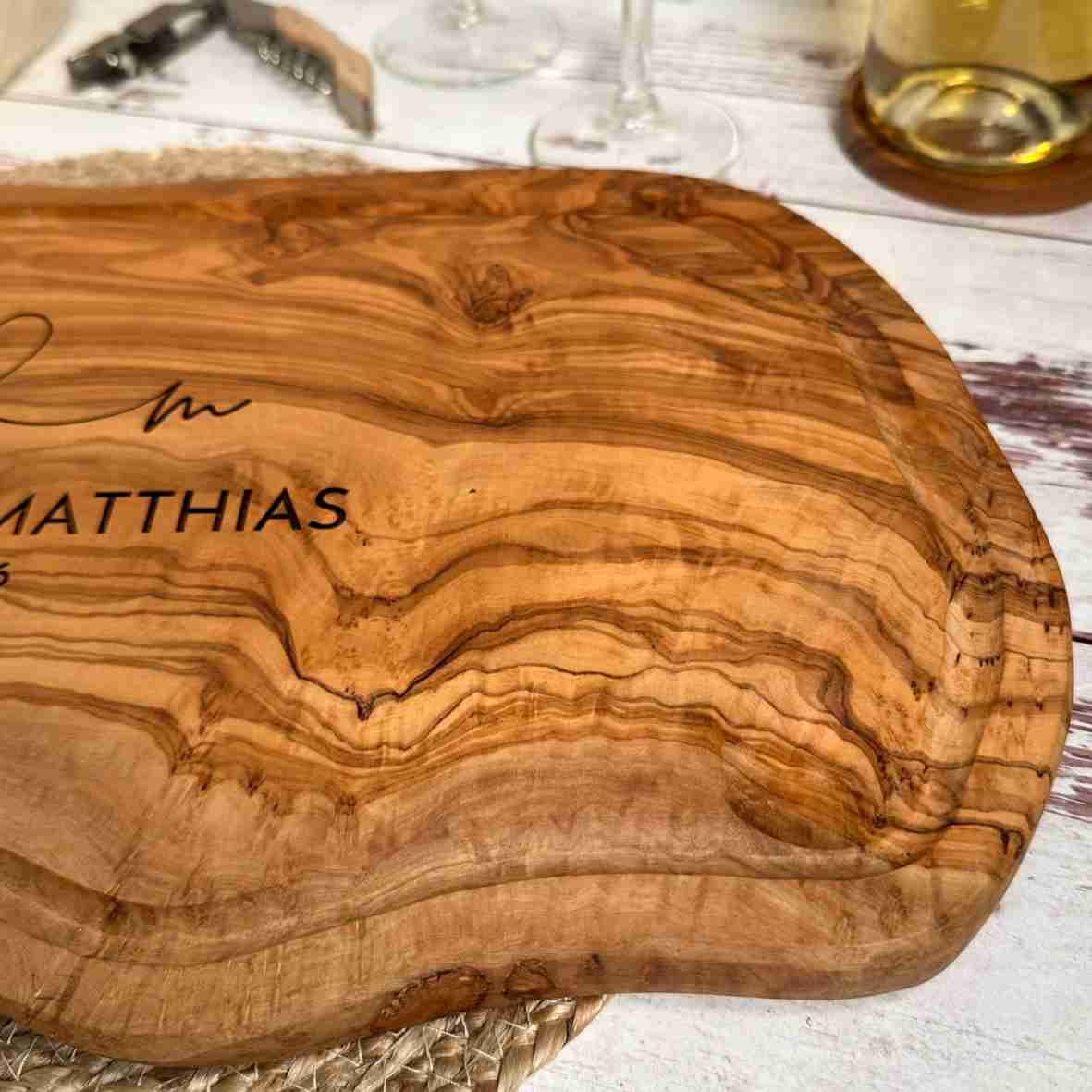 Personalisiertes Olivenholzbrett mit Herz-Gravur, Namen und Datum.