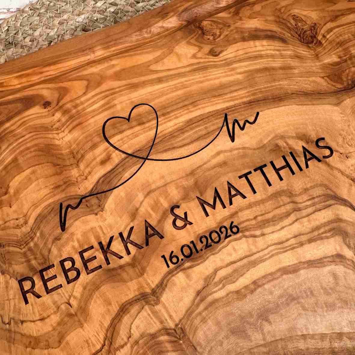 Personalisiertes Olivenholzbrett mit Herz-Gravur, Namen und Datum.