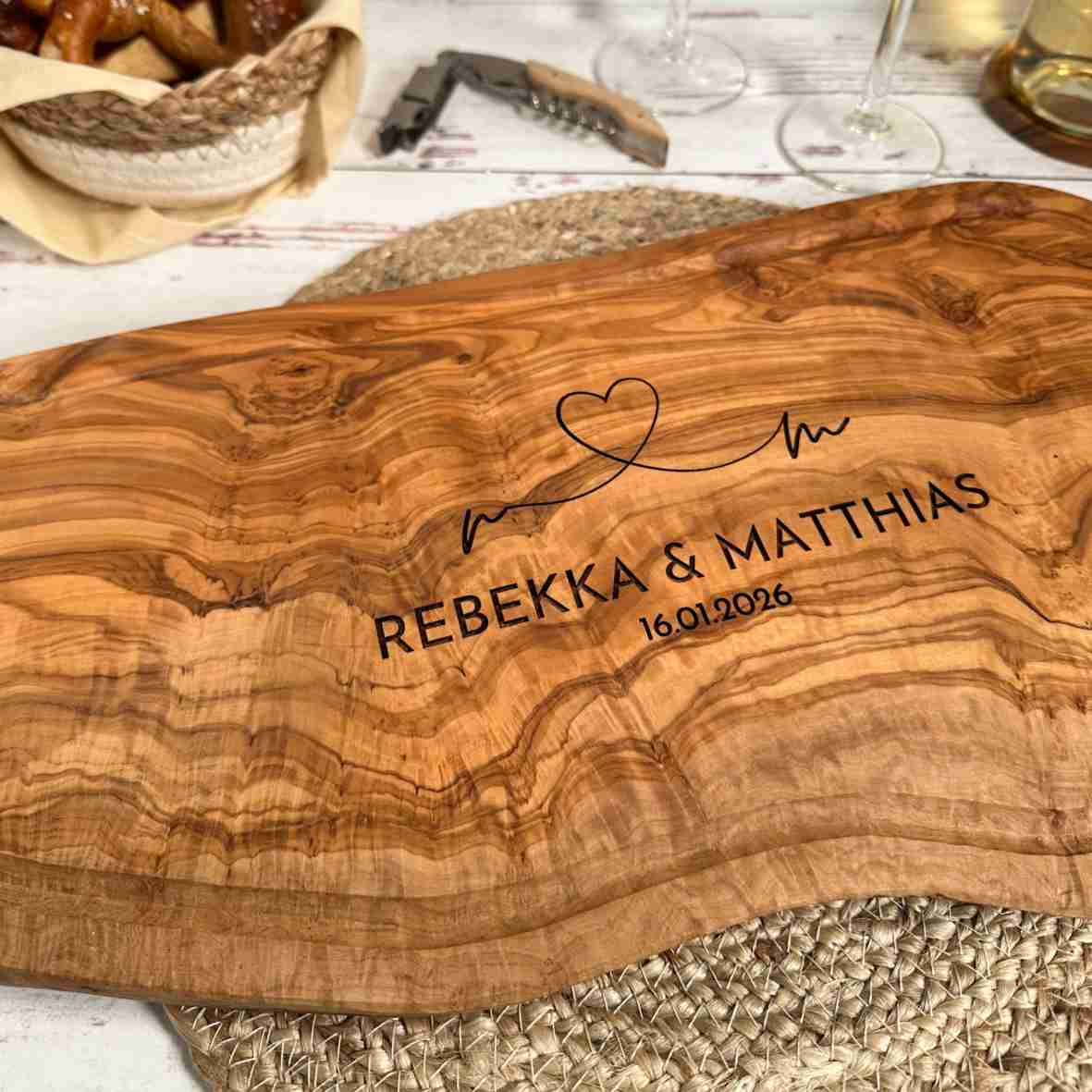 Personalisiertes Olivenholzbrett mit Herz-Gravur, Namen und Datum.