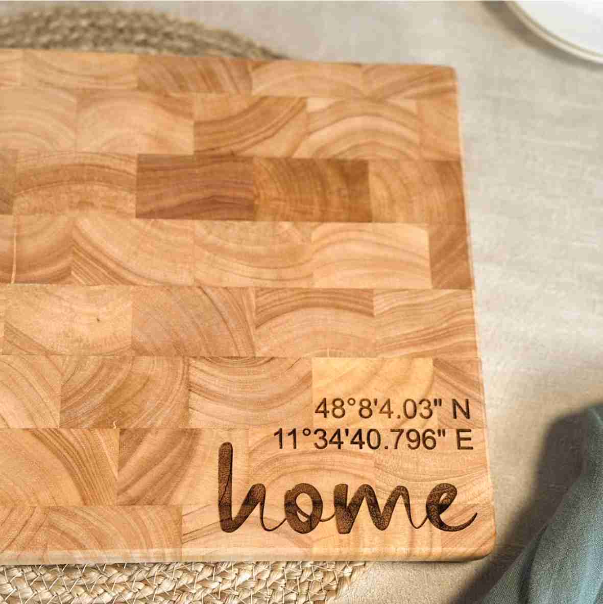 Personalisiertes Schneidebrett aus Stirnholz mit graviertem „home“-Motiv, individuellen Namen und GPS-Koordinaten als einzigartiges Geschenk.
