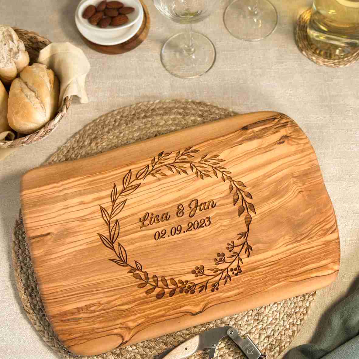 Personalisiertes Schneidebrett aus Olivenholz mit floralem Kranz, graviertem Namen „Lisa & Jan“ und Datum – romantisches Geschenk zur Hochzeit oder Verlobung.