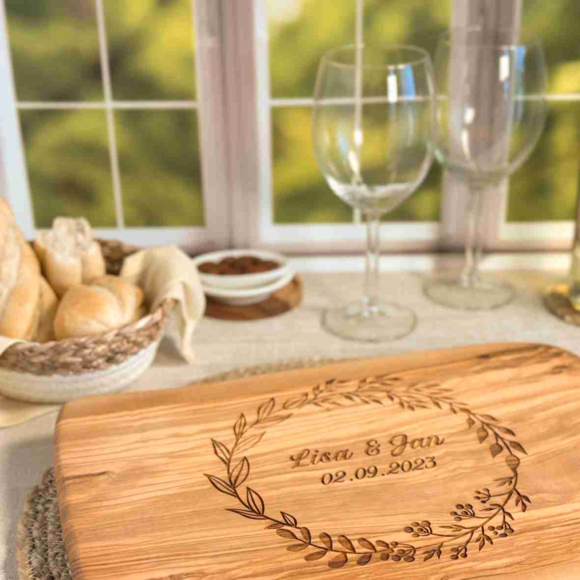 Personalisiertes Schneidebrett aus Olivenholz mit floralem Kranz, graviertem Namen „Lisa & Jan“ und Datum – romantisches Geschenk zur Hochzeit oder Verlobung.
