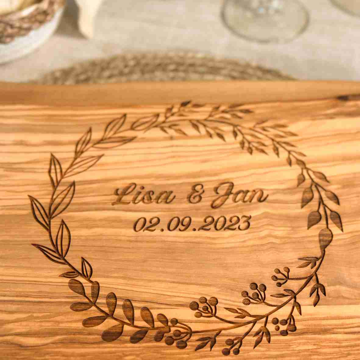 Personalisiertes Schneidebrett aus Olivenholz mit floralem Kranz, graviertem Namen „Lisa & Jan“ und Datum – romantisches Geschenk zur Hochzeit oder Verlobung.